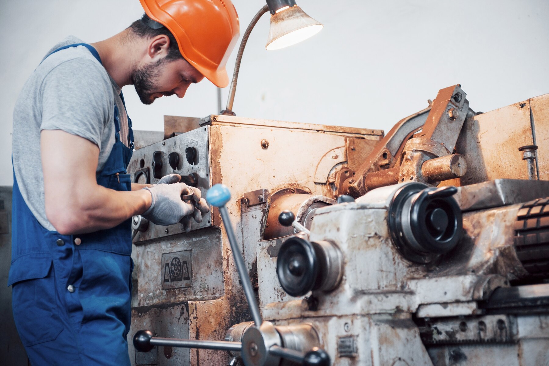 Worker in a safety helmet welding parts of a ship